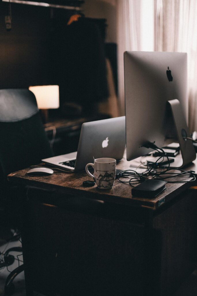 A cozy home office with modern computers and warm lighting for productivity.