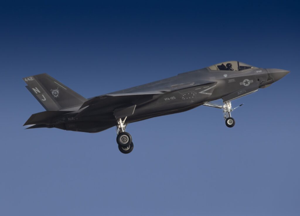 A military jet in midair against a clear blue sky, showcasing aviation technology