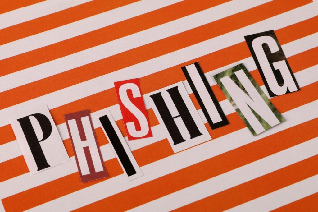 Phishing headline with cut-out letters on an orange striped background illustrating cybersecurity threats.