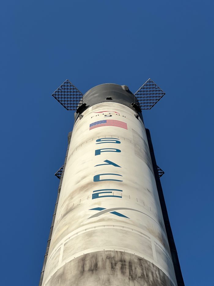 Close-up view of a SpaceX rocket against a clear blue sky, showcasing its structure and design.