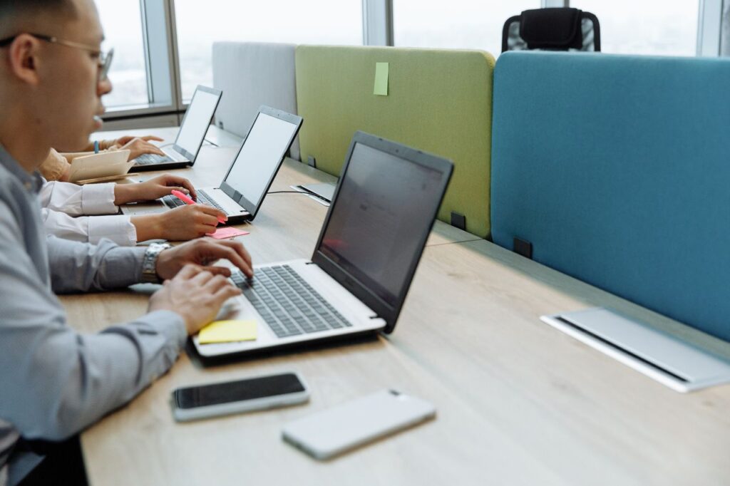 Colleagues working diligently at shared desks with laptops in a modern office space.